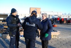 policjanci rozdają ulotki seniorom na targowisku