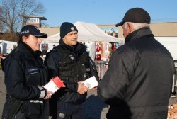 policjanci rozdają ulotki seniorom na targowisku