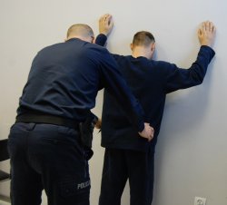 policjant przeszukuje zatrzymanego męzczynę